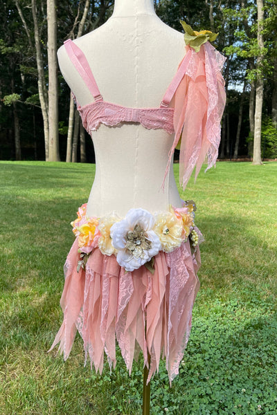 Mannequin wearing a pink dress with floral details outdoors.